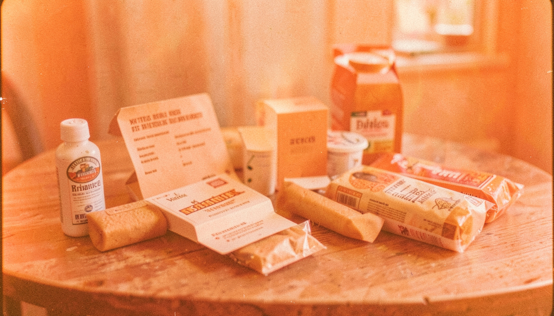Warm orange-toned product display featuring everyday review items arranged on a wooden table under soft natural light, with visible film grain.